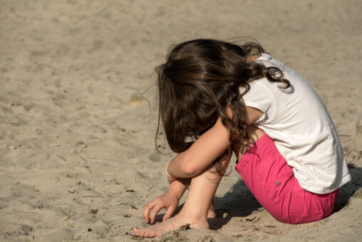 Small sad girl on the beach