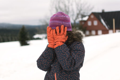 Little girl covers her face in winter