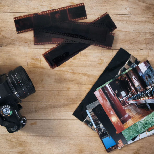 Camera Film And Photos On Wooden Background