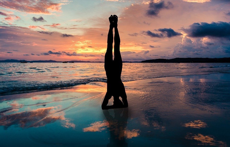 yoga stand in hands silhouette, sunset beach, zen position by the sea
