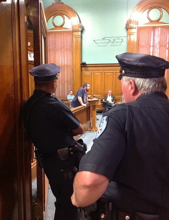 city council meeting, police officers watching, police officers